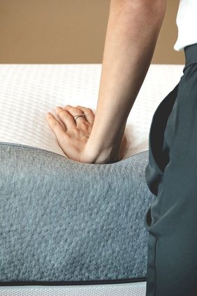 A hand pressing into a Comfortaire mattress